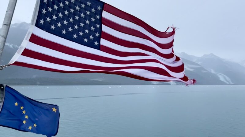 海風に吹かれるアメリカ国旗とアラスカの周旗